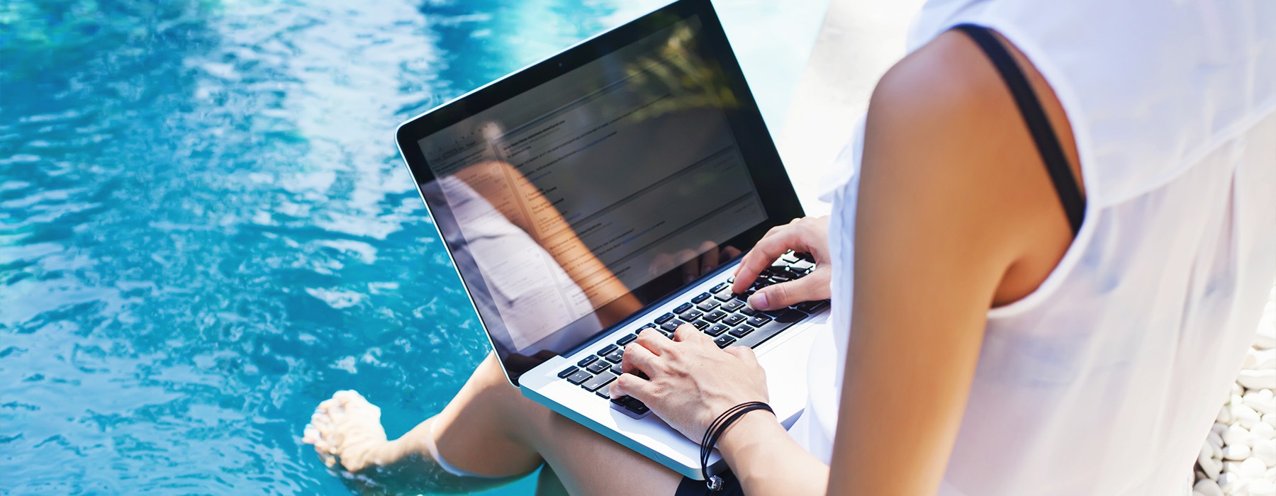 a person on a laptop with their feet in a pool